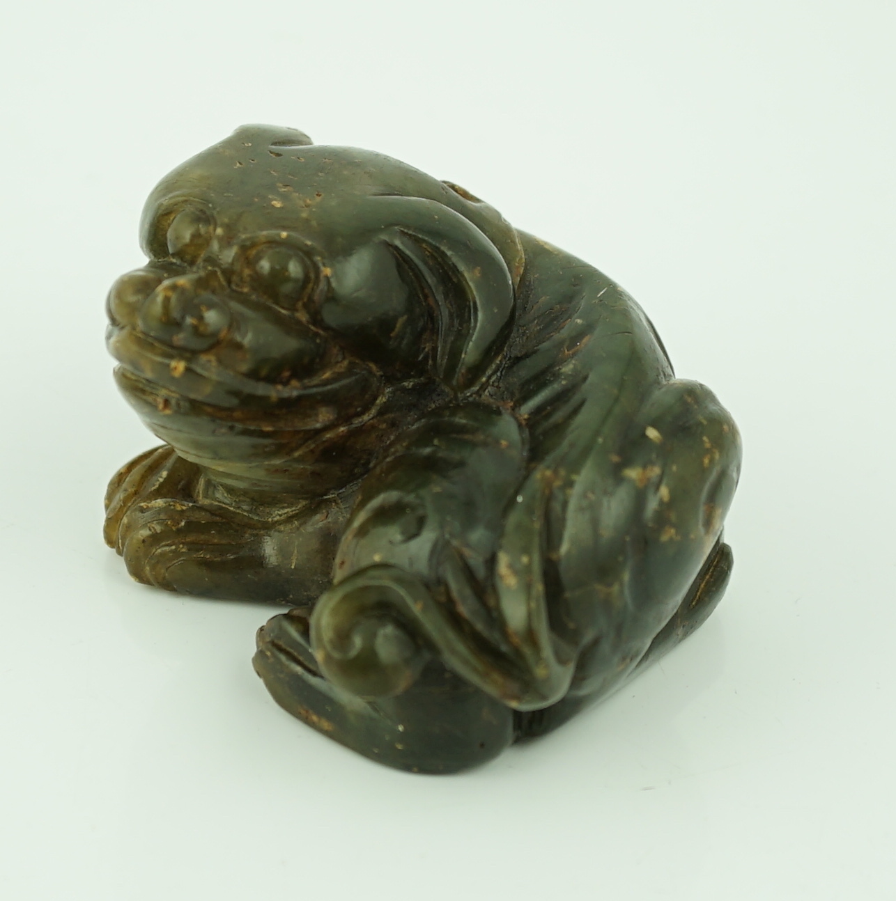 A Chinese Ming green soapstone figure of a recumbent lion-dog, 16th/17th century